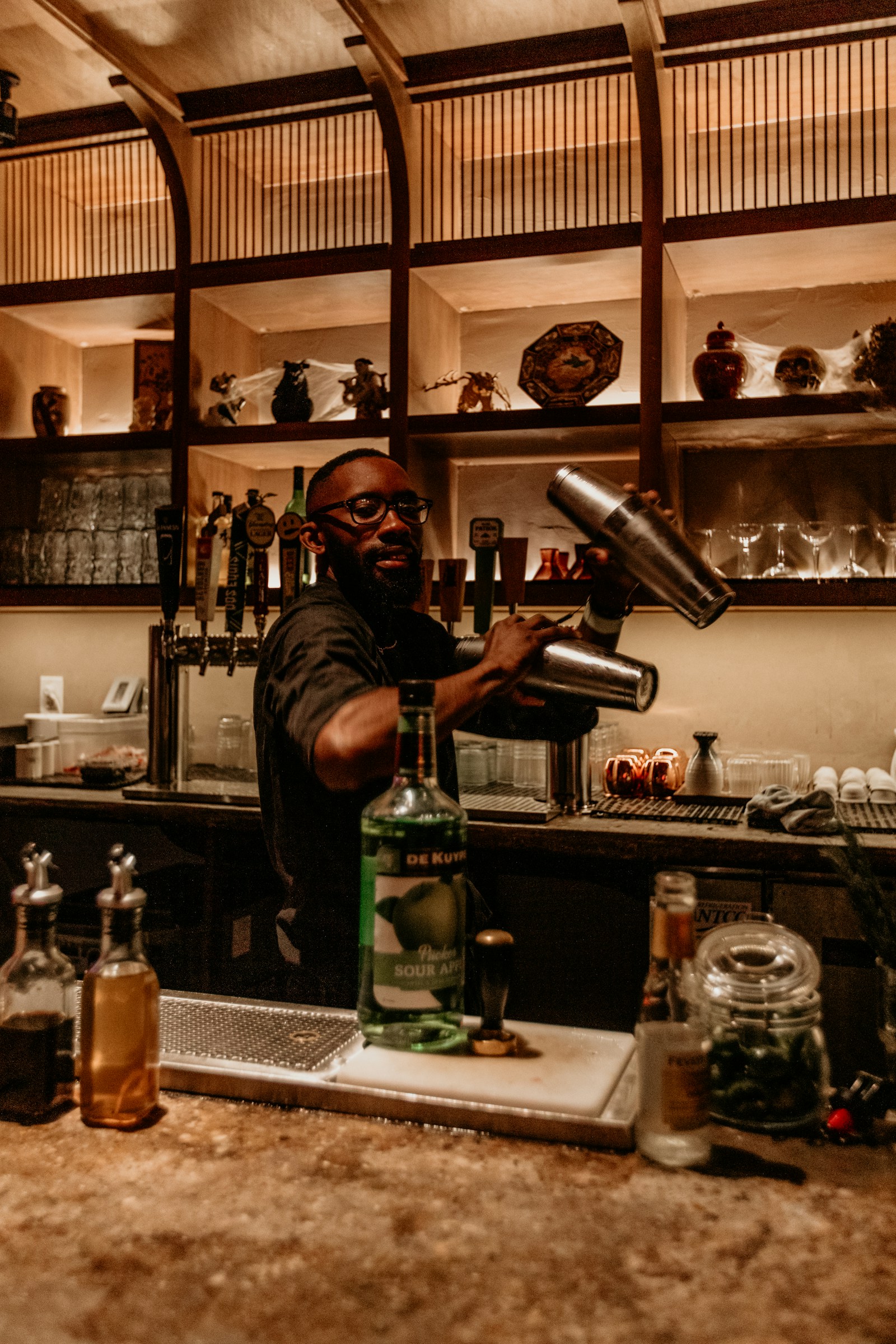 A bartender pouring a cocktail at a modern bar counter